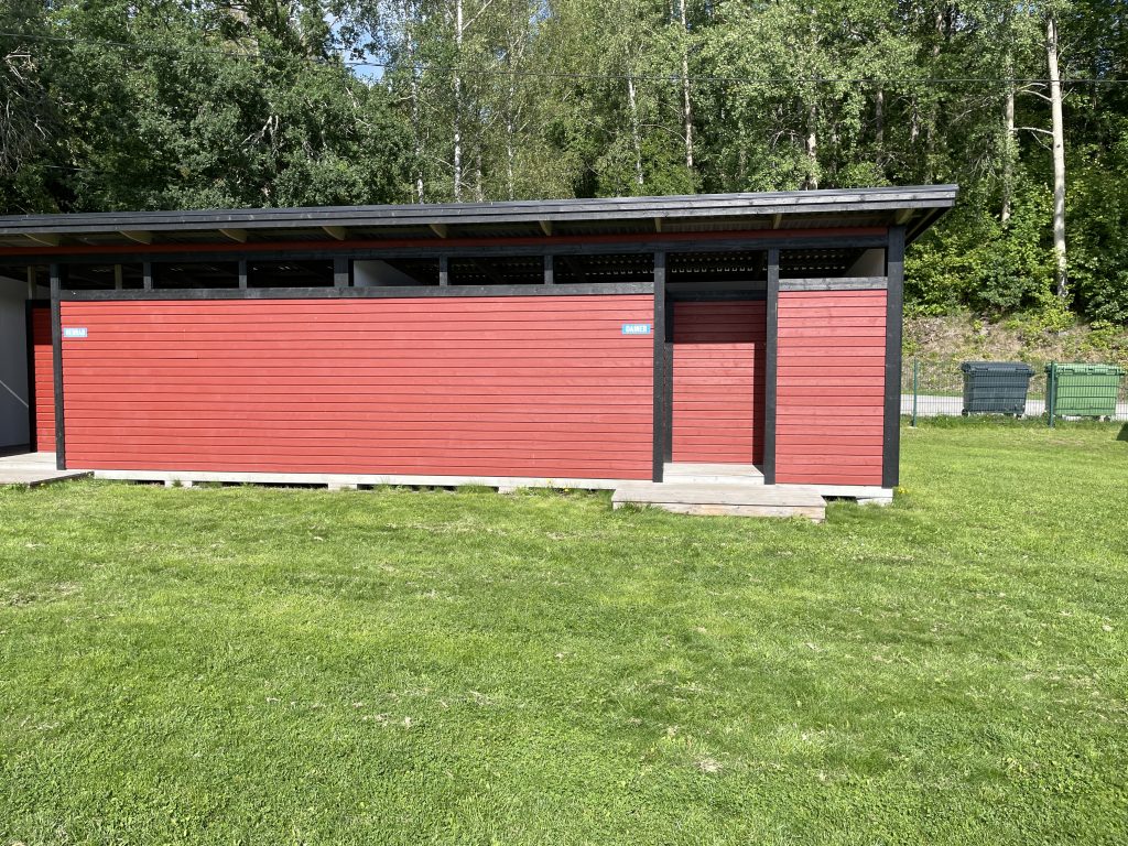 a small red wooden building with changing rooms for guys and gals